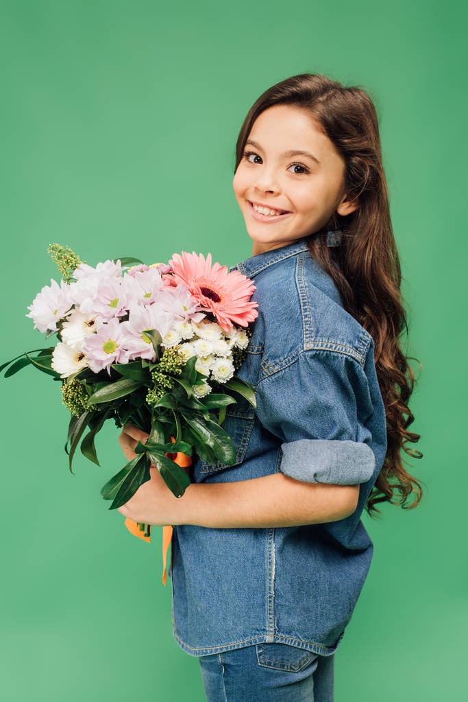 criança feliz adorável com buquê de flores olhando para a câmera isolada no verde
 - Foto, Imagem