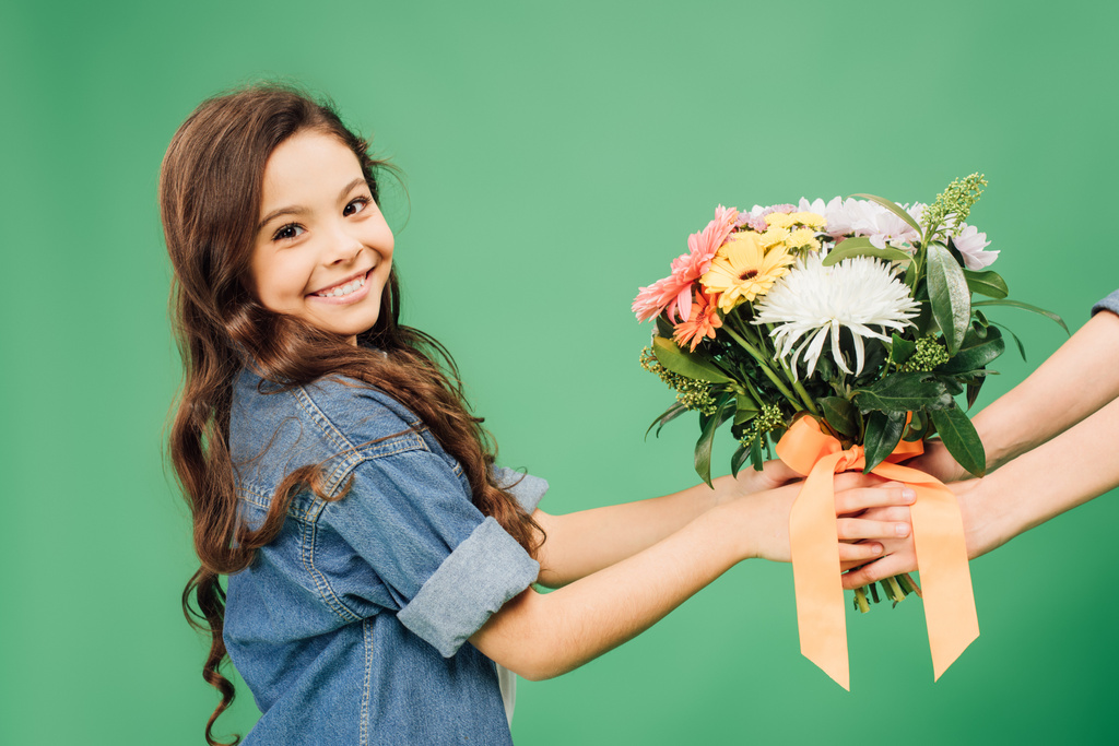 preteen smiling child holding flowers isolated on green - Photo, Image