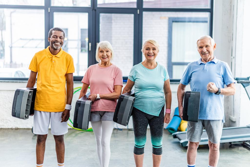 Multikulturelle Senioren halten Step-Podeste im Fitnessstudio - Foto, Bild