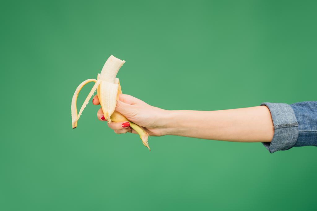 przycięte widzenia kobietę pół banana w ręku na zielonym tle - Zdjęcie, obraz