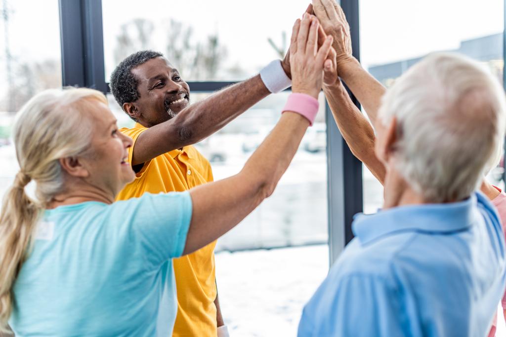 felice anziani sportivi multiculturali mettendo le mani insieme in palestra
 - Foto, immagini