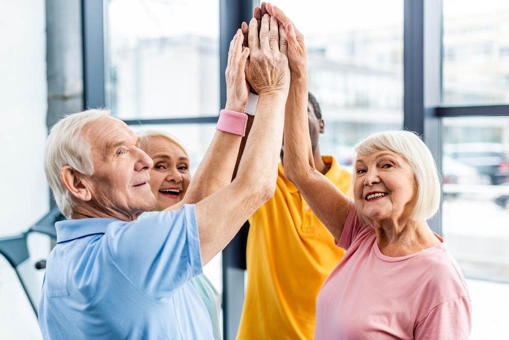 anziani felici sportivi multiculturali mettere le mani insieme in palestra
 - Foto, immagini