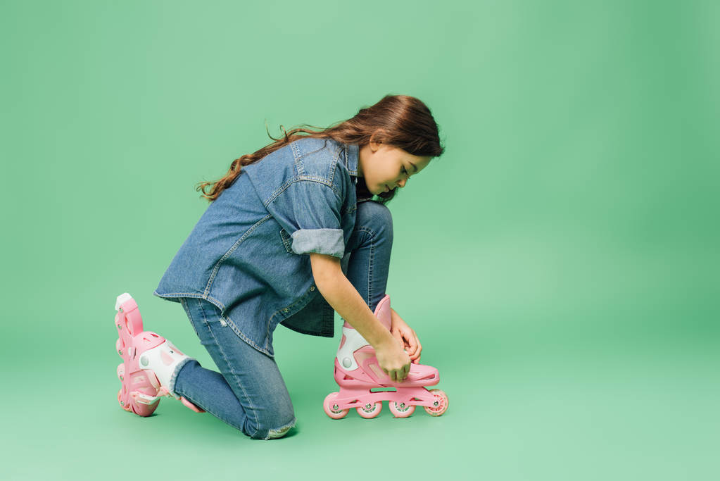 Kind in Jeans mit Rollerblades auf grünem Hintergrund - Foto, Bild