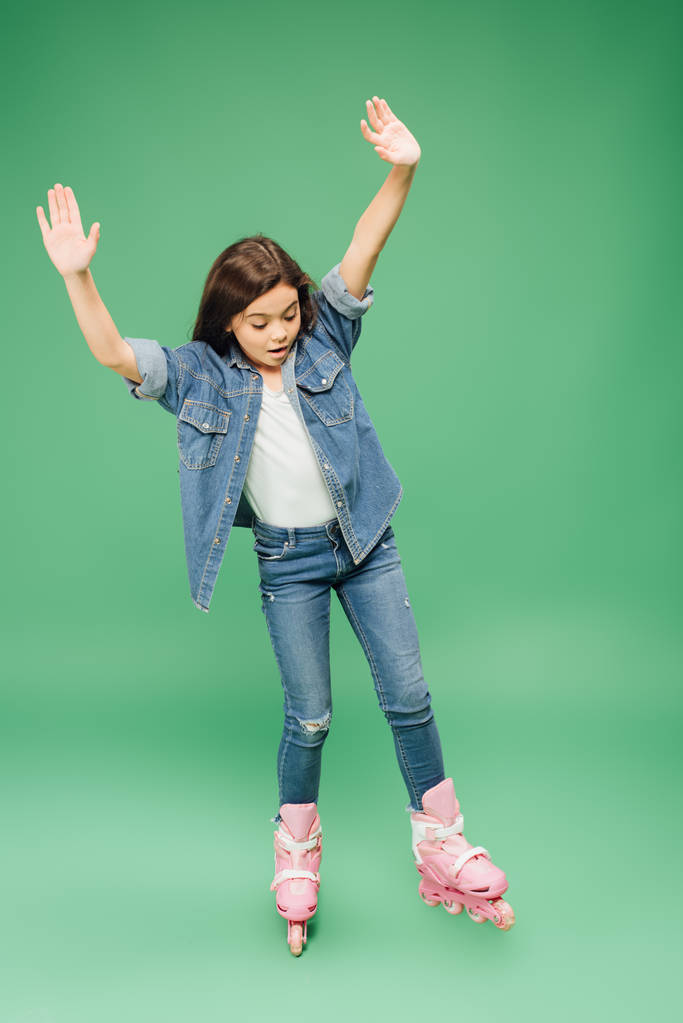 παιδί rollerblading με απλωμένα τα χέρια σε πράσινο φόντο - Φωτογραφία, εικόνα