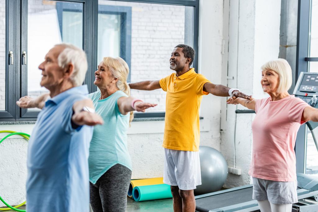 foco seletivo de atletas seniores multiétnicos síncronos fazendo exercício na sala de esportes
 - Foto, Imagem