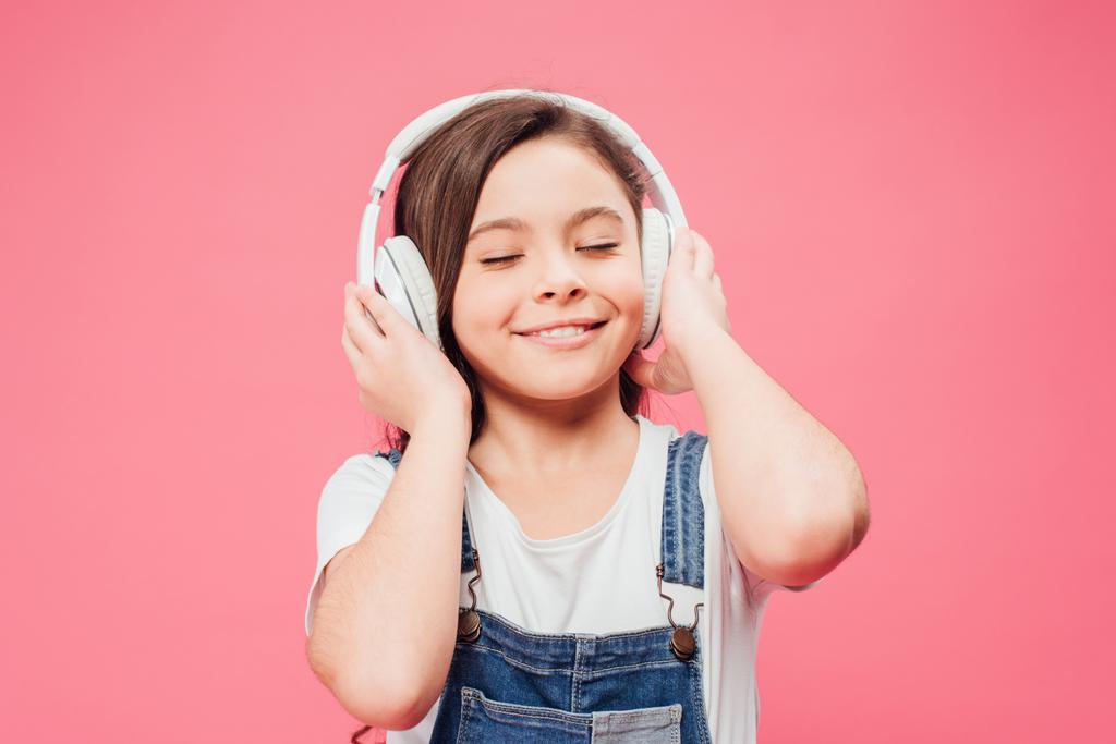 笑顔の子ピンクの分離のヘッドフォンで音楽を聴く  - 写真・画像