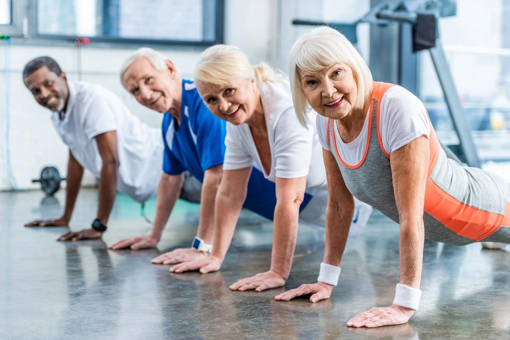 heureux sportifs multiculturels seniors faisant planche à la salle de gym
 - Photo, image