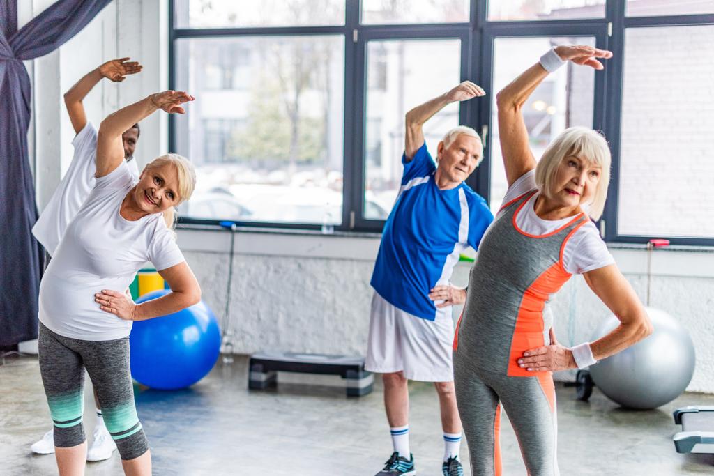 joyeux souriant sportifs âgés multiethniques exercice synchrone à la salle de sport
 - Photo, image