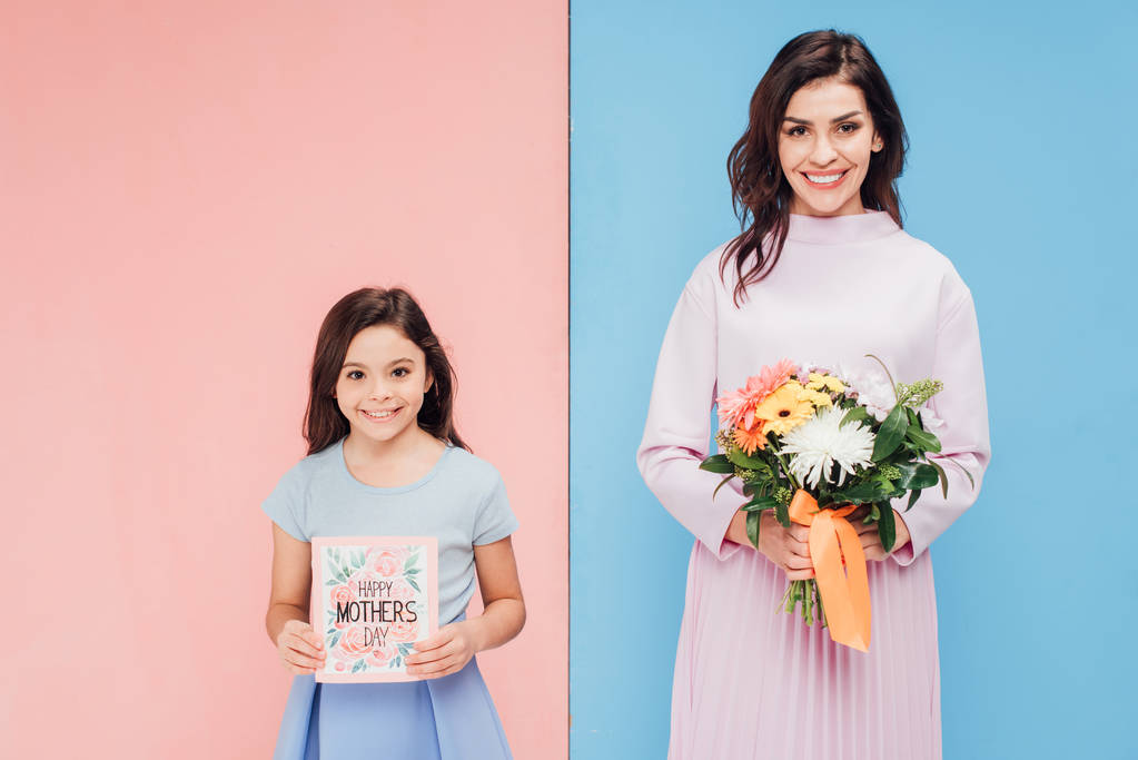 чарівна дитина і приваблива жінка тримає подарунки, посміхаючись дивитися на камеру на синьо-рожевому фоні
 - Фото, зображення