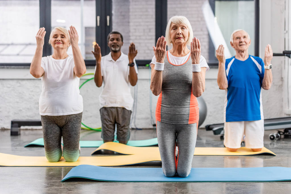 senior multicultural sportspeople synchronous exercising on fitness mats at gym - Photo, Image