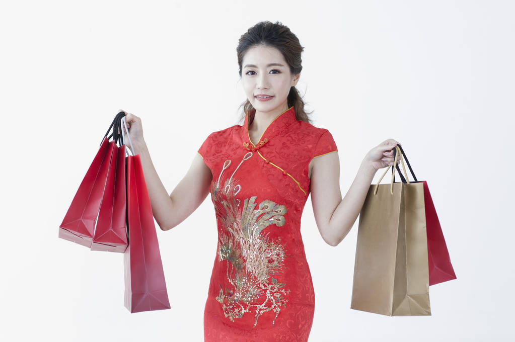 Mladá Čínská žena nosí cheongsam drží nějaké dárky a usmívá se na kameru - Fotografie, Obrázek
