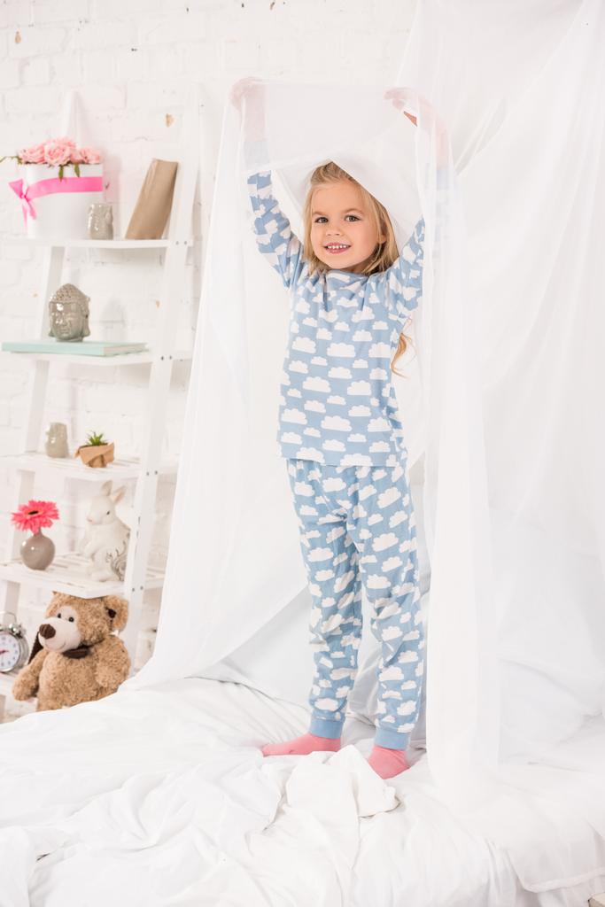 enfant souriant en pyjama debout sur le lit et toucher la verrière
 - Photo, image