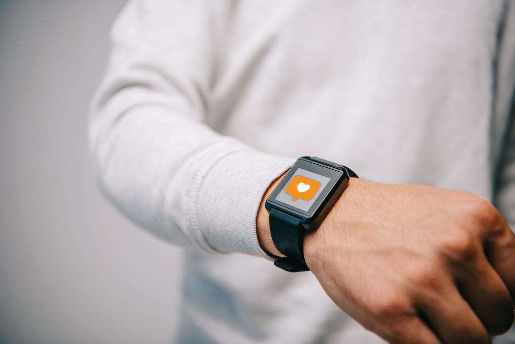 vista ritagliata dell'uomo con smartwatch con icona multimediale come
 - Foto, immagini