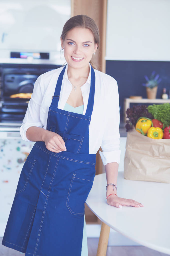 Πορτρέτο της νεαρής γυναίκας στέκεται με τα χέρια σταυρωμένα σε φόντο κουζίνα - Φωτογραφία, εικόνα
