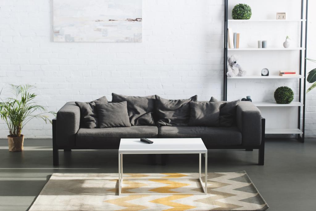 moderne Wohnzimmereinrichtung mit grauem Sofa, Tisch und Bücherregalen - Foto, Bild