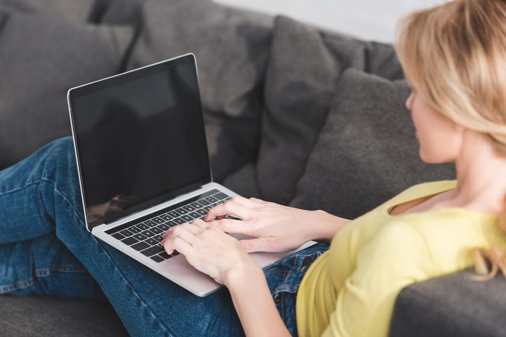 cropped shot of woman using laptop with blank screen on couch - Photo, Image