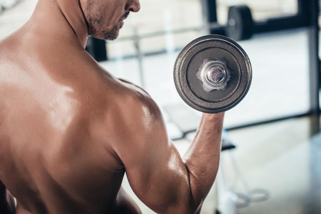 cropped image of shirtless sportsman training with dumbbell in gym  - Photo, Image