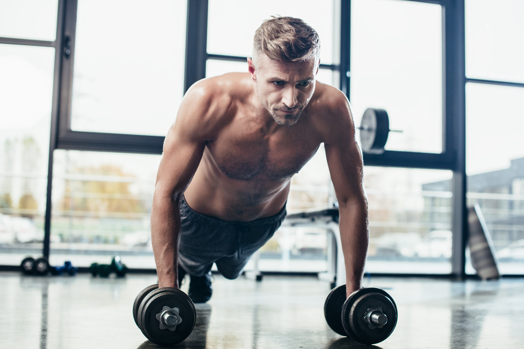 красивий м'язистий спортсмен тренування з гантелями і робити дошку в спортзалі
  - Фото, зображення
