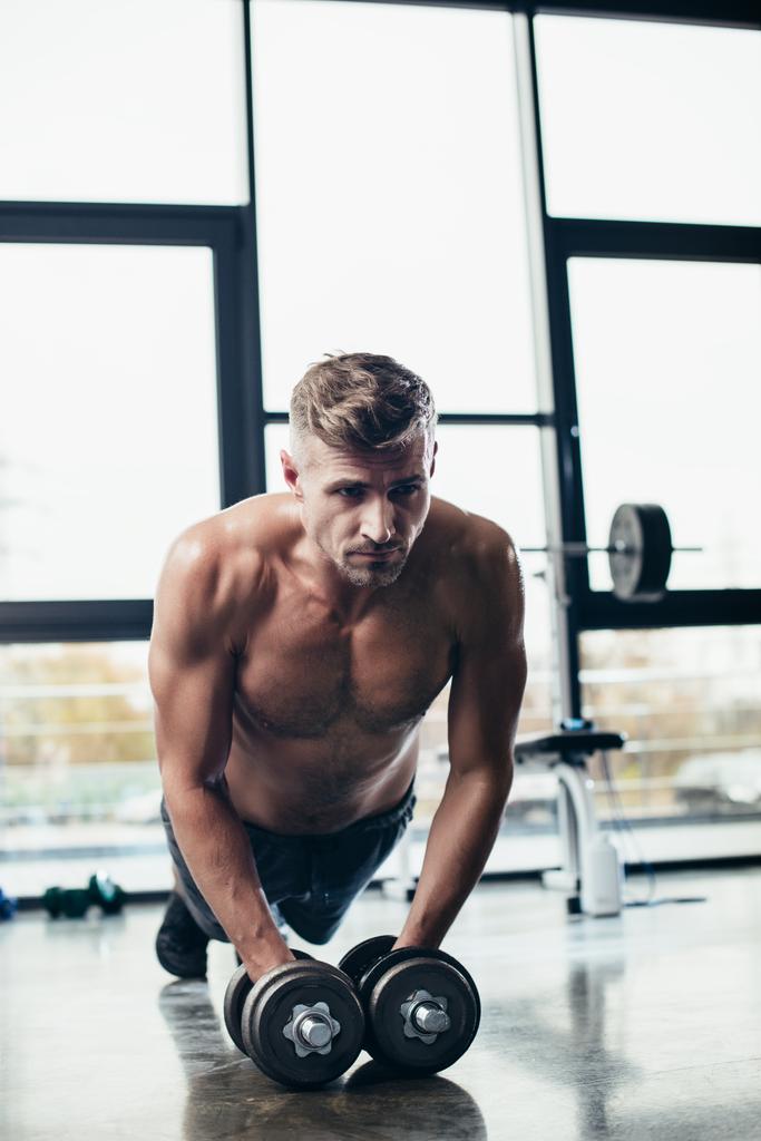 bonito muscular desportista fazendo prancha no halteres no ginásio
  - Foto, Imagem
