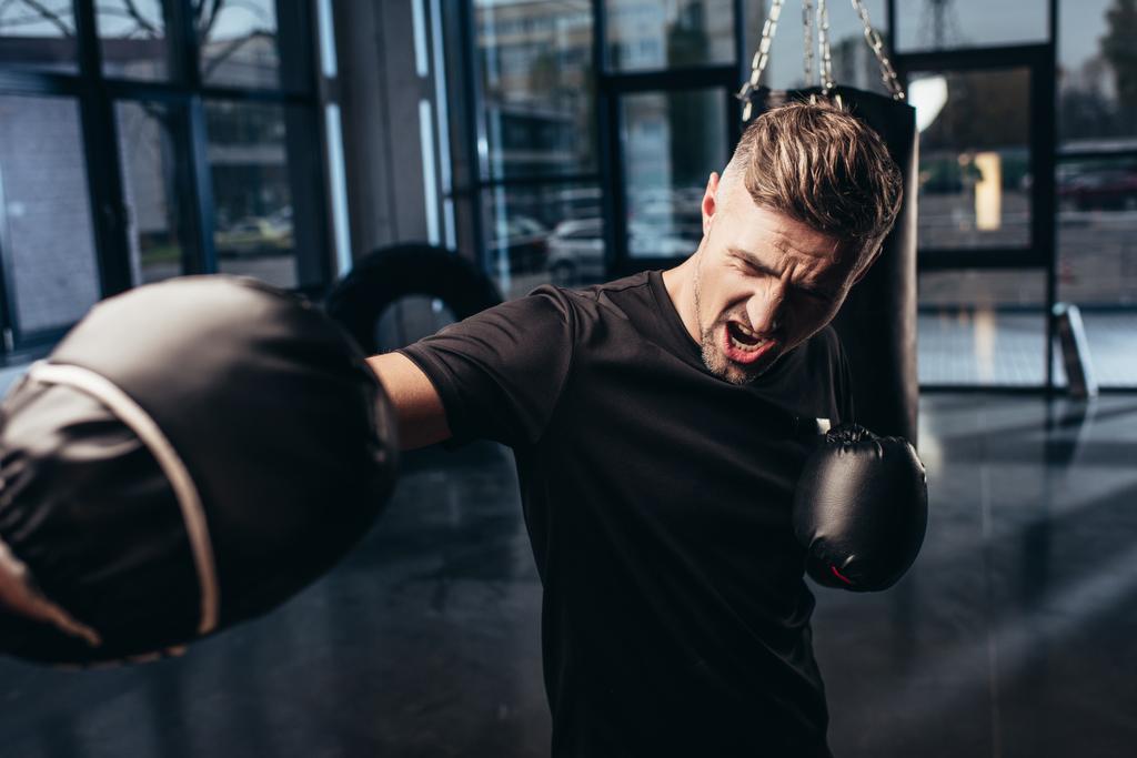 knappe bokser traint met trainer en schreeuwen in sportschool - Foto, afbeelding