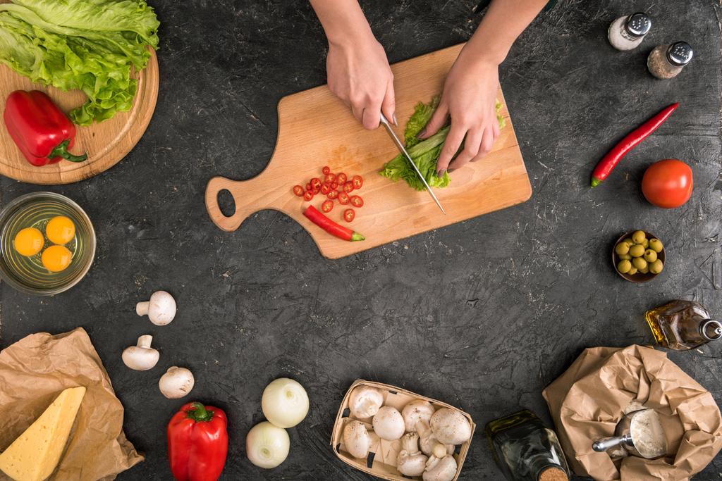 vista ritagliata della donna che taglia verdure sul tagliere con ingredienti della pizza su sfondo grigio
  - Foto, immagini