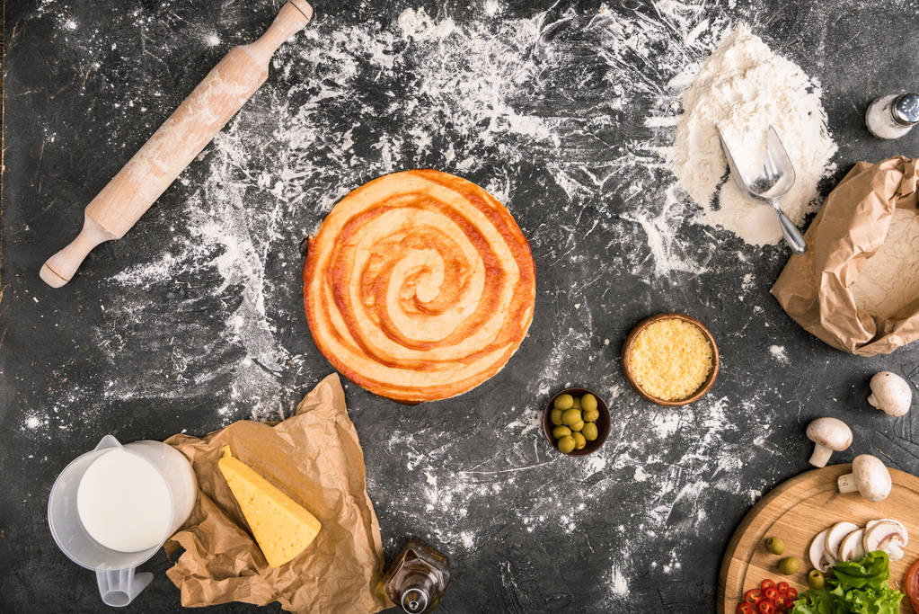 top view of uncooked pizza, ingredients and rolling pin on grey background with flour  - Photo, Image