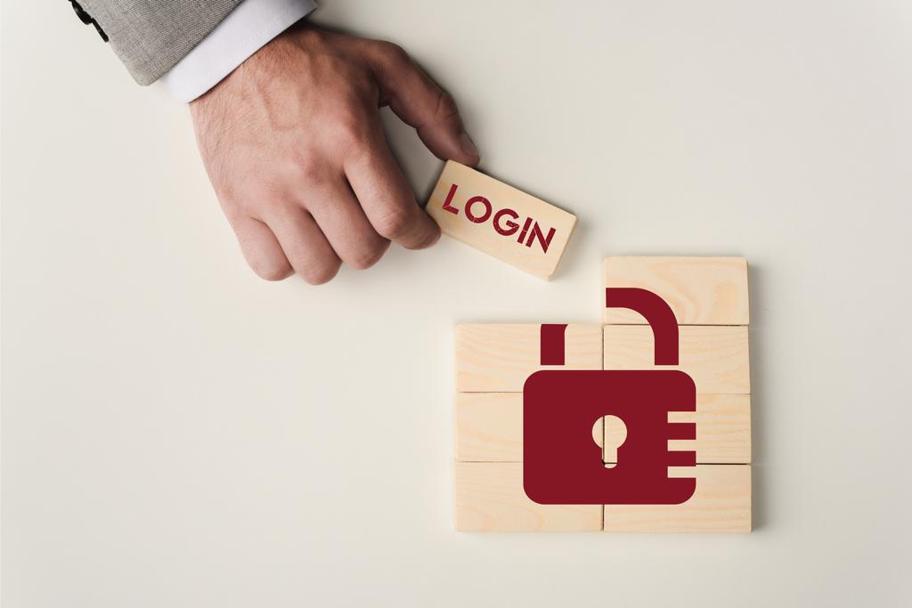 partial view of man holding brick with 'login' lettering over wooden blocks with lock icon isolated on white - Photo, Image