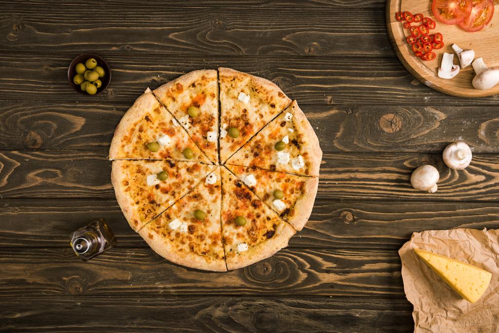木製テーブルの上の食材とおいしいチーズのピザの上から見る - 写真・画像