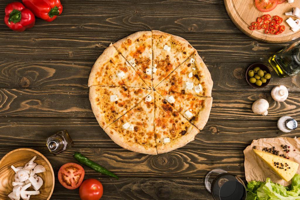 食材や木製のテーブルの上の野菜とチーズのピザ - 写真・画像