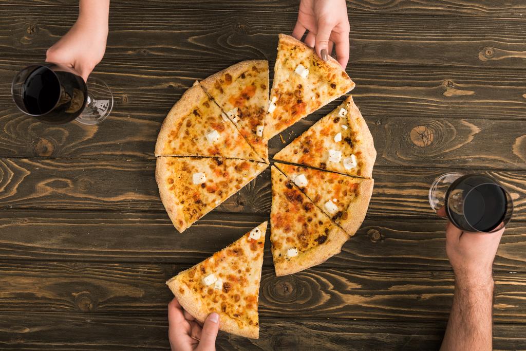 vue dégagée du couple en train de dîner avec pizza au fromage et vin rouge à table en bois
 - Photo, image