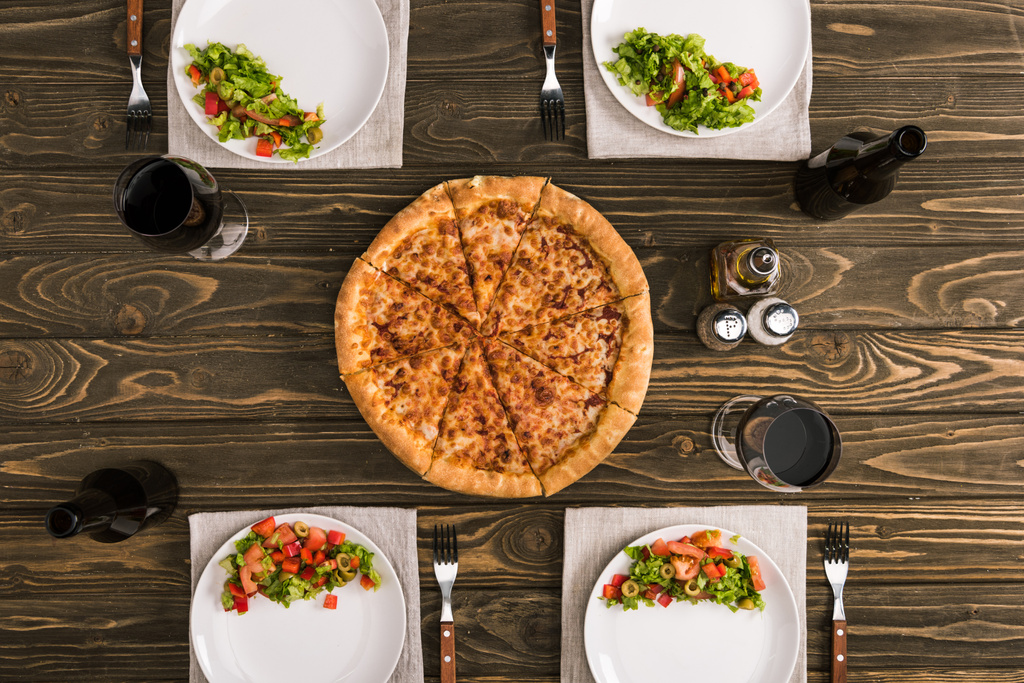 mesa con pizza y copas de vino sobre mesa de madera
 - Foto, Imagen