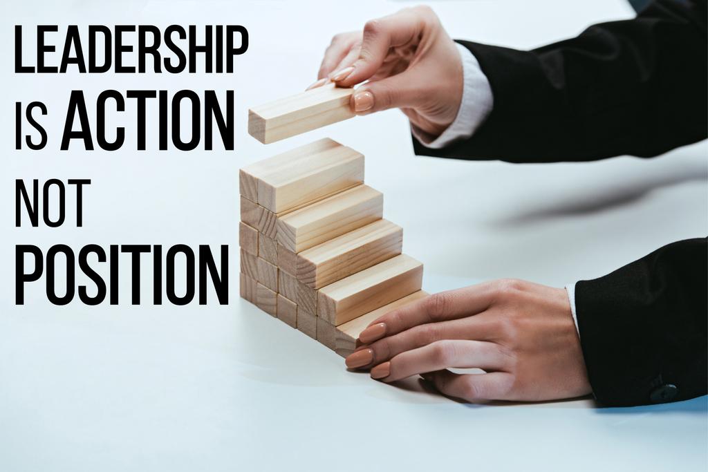 cropped view of woman building career ladder with wooden blocks, 'leadership is action not position' lettering on foreground - Photo, Image