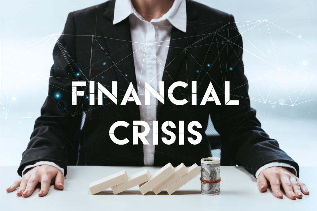 visão cortada de empresária com blocos de madeira e rolo de dinheiro na mesa e letras de "crise financeira" em primeiro plano
 - Foto, Imagem