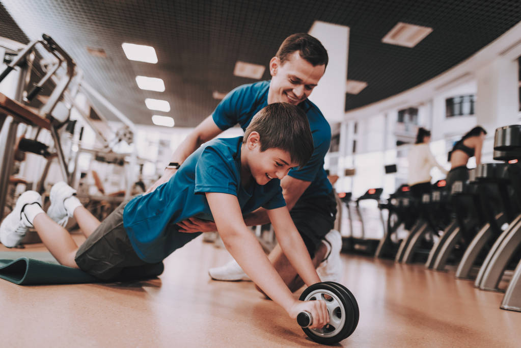 Молодой отец и сын делают упражнения в спортивном клубе
 - Фото, изображение