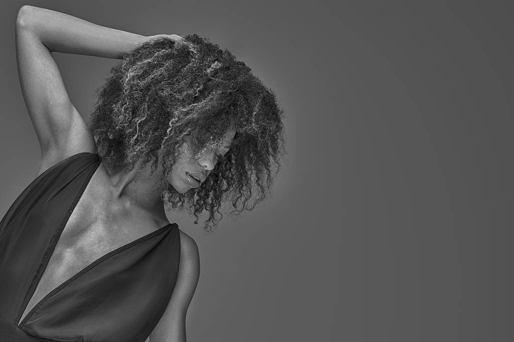 Элегантная красивая африканская американка позирует в сексуальном черном платье. Снимок студии
. - Фото, изображение