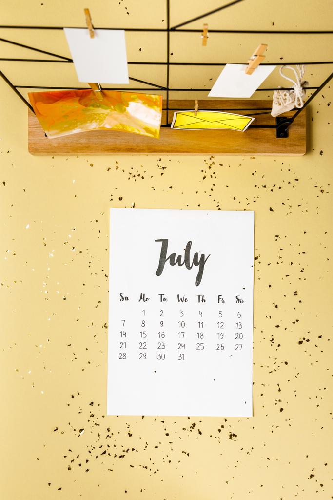 üzerinde bej altın konfeti ile Temmuz takvim ve kartları clothespins ile üstten görünüm - Fotoğraf, Görsel