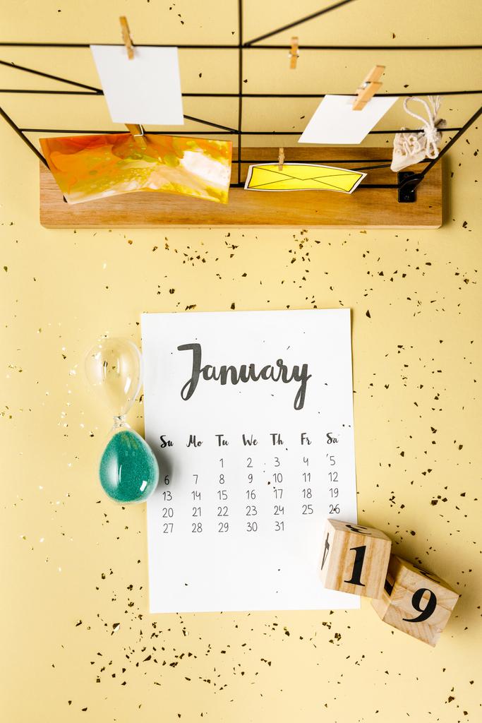 κάτοψη του ημερολόγιο Ιανουάριος με χρυσές κομφετί και κάρτες με μανταλάκια σε μπεζ - Φωτογραφία, εικόνα