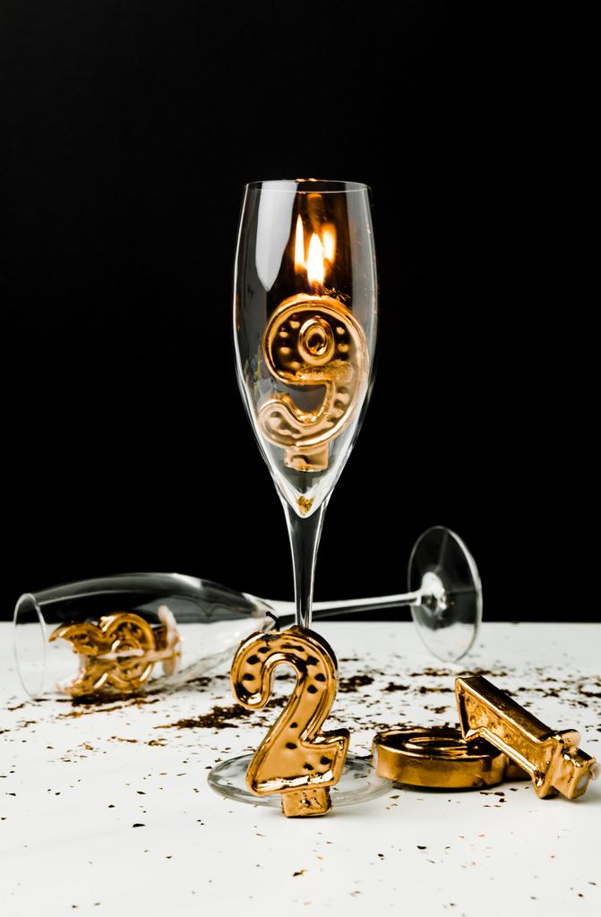 vista de cerca de copas de champán y números dorados de 2019 con vela encendida en negro
  - Foto, Imagen