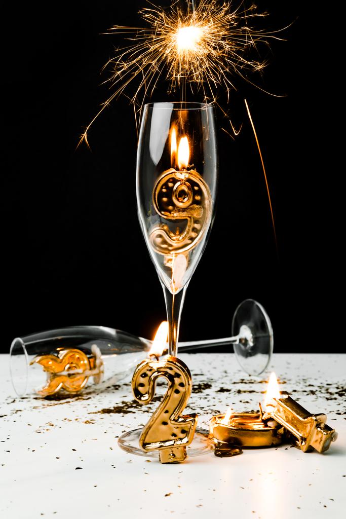 sparkler, viinilasit ja kultainen 2019 numerot kynttilöillä mustalla
  - Valokuva, kuva