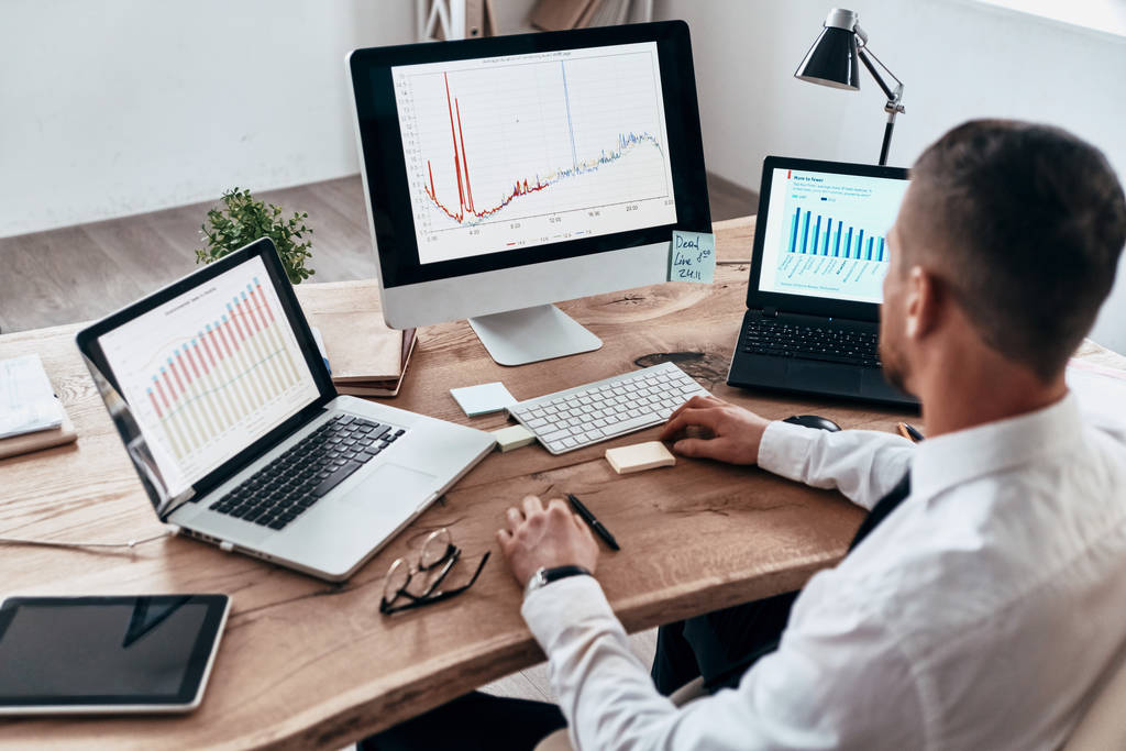 Аналіз рівня продажів, бізнесмен використовує комп'ютер і ноутбук за офісним столом
 - Фото, зображення