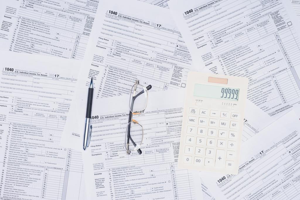το Top view αριθμομηχανή, στυλό και γυαλιά με φορολογικά έντυπα σε φόντο - Φωτογραφία, εικόνα