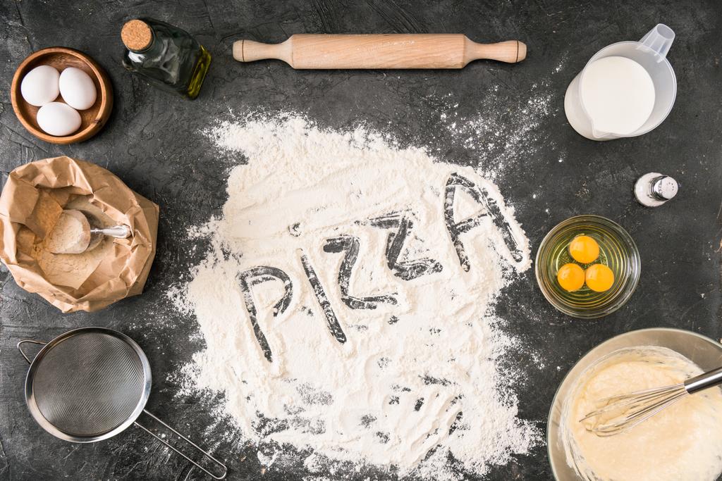 κάτοψη του τη λέξη «πίτσα» κατασκευασμένα από αλεύρι με υλικά και σκεύη σε γκρίζο φόντο - Φωτογραφία, εικόνα