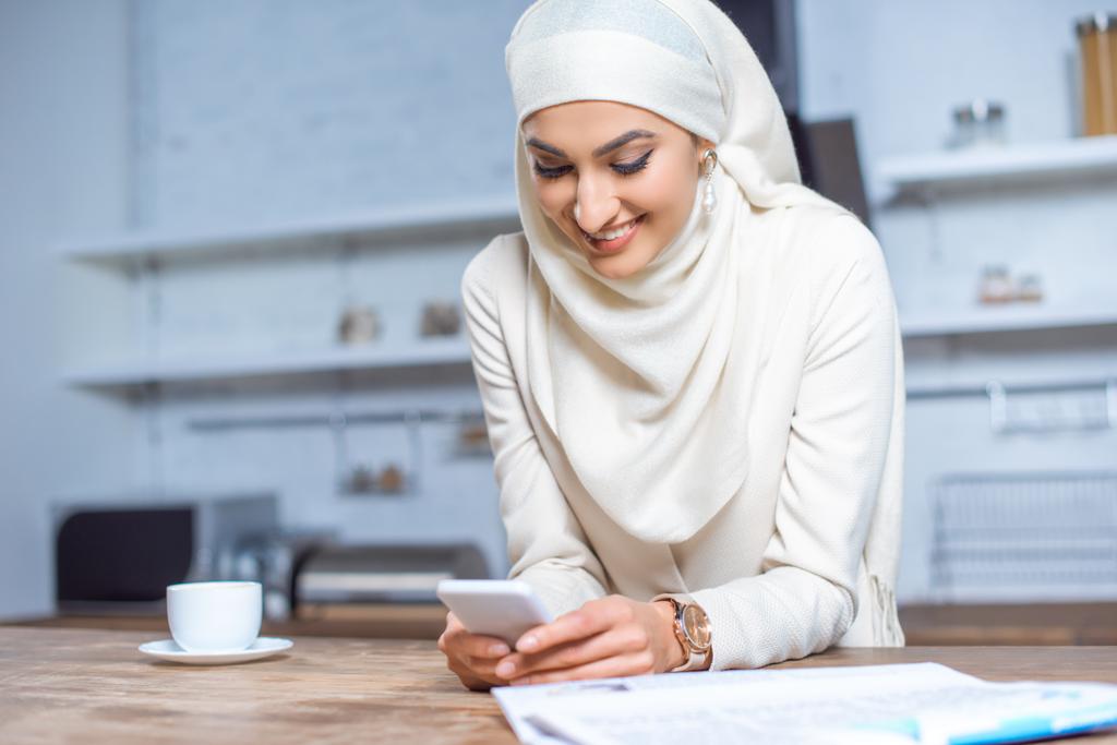 belle jeune femme musulmane souriante utilisant un smartphone à la maison
  - Photo, image