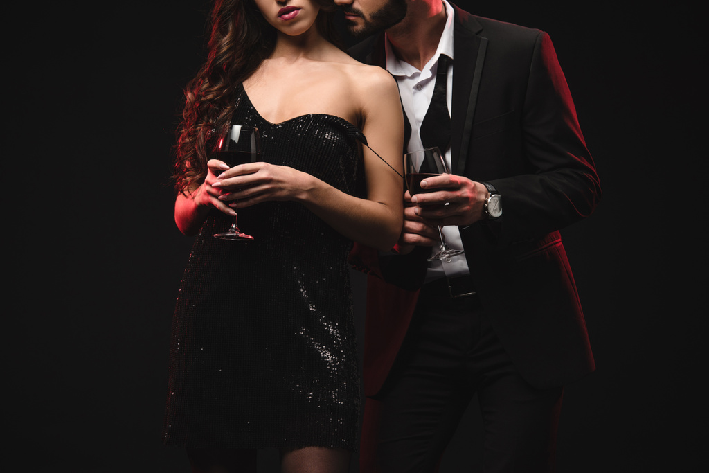 vue recadrée du couple séduisant tenant des verres avec vin rouge isolé sur noir
  - Photo, image