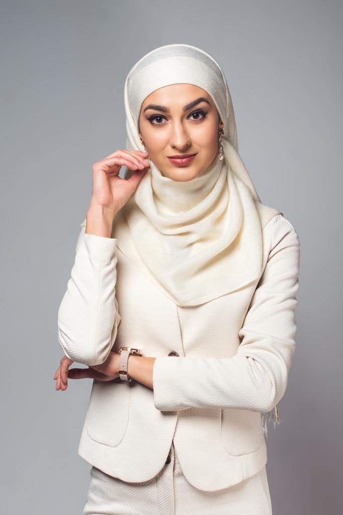 Porträt einer schönen jungen Muslimin, die isoliert auf grau in die Kamera lächelt - Foto, Bild
