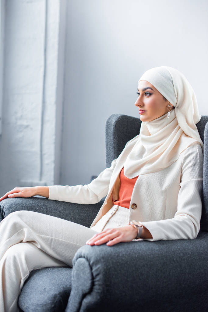 jeune femme musulmane assise sur une chaise et regardant loin
  - Photo, image