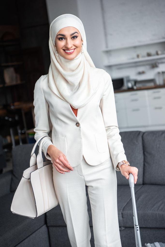 belle jeune femme musulmane tenant une valise et souriant à la caméra
  - Photo, image