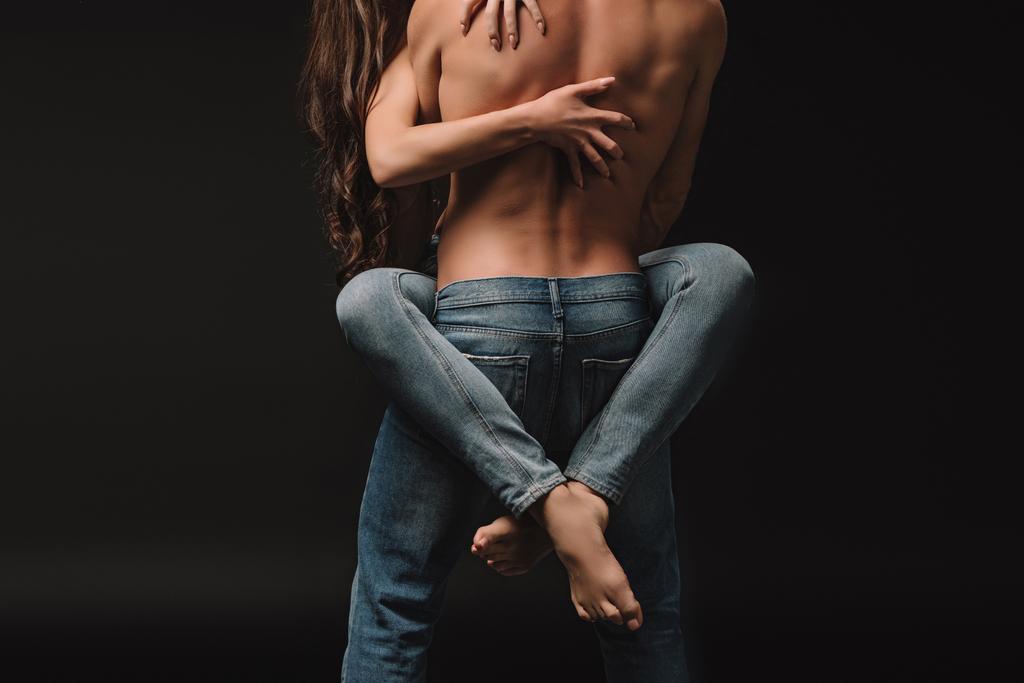 abgeschnittene Ansicht eines leidenschaftlichen Paares, das sich isoliert auf Schwarz umarmt - Foto, Bild