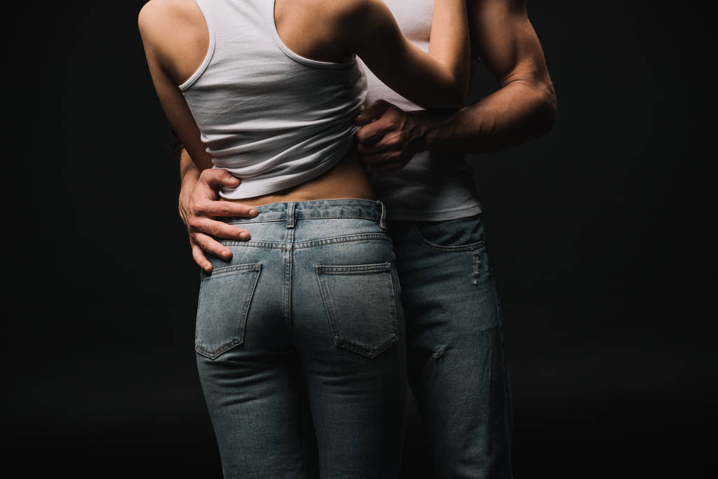 cropped view of couple in white singlets and jeans isolated on black - Photo, Image