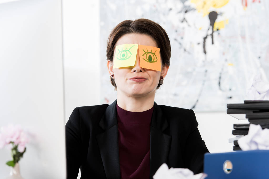 mujer de negocios mueca sentado con pegatinas en los ojos en la oficina
 - Foto, Imagen